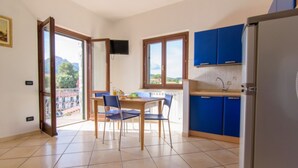 Una cucina con zona pranzo, una TV a parete e vista sull'esterno attraverso le finestre.