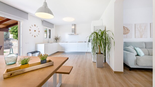 Une cuisine moderne avec des armoires blanches, un plan de travail en bois et un luminaire suspendu.