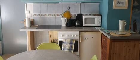 Une cuisine avec des meubles de couleur bleue, un four à micro-ondes, une cuisinière et une table à manger avec des chaises.