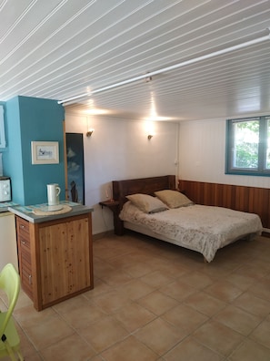 Una habitación con cama, escritorio, silla, ventana y lámpara fijada a la pared.