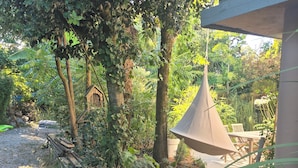 A garden area with a wooden bench, a hanging light fixture, and a variety of plants. - Pleasant studio on the ground floor with private terrace and garden. 2 steps from the beach (Pornic)