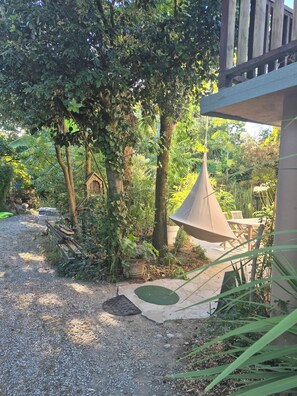 A garden area with a wooden bench, a hanging light fixture, and a variety of plants.