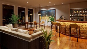 Una sala de estar moderna con un sofá, sillas, una mesa de centro y una zona de bar con estantes llenos de botellas.