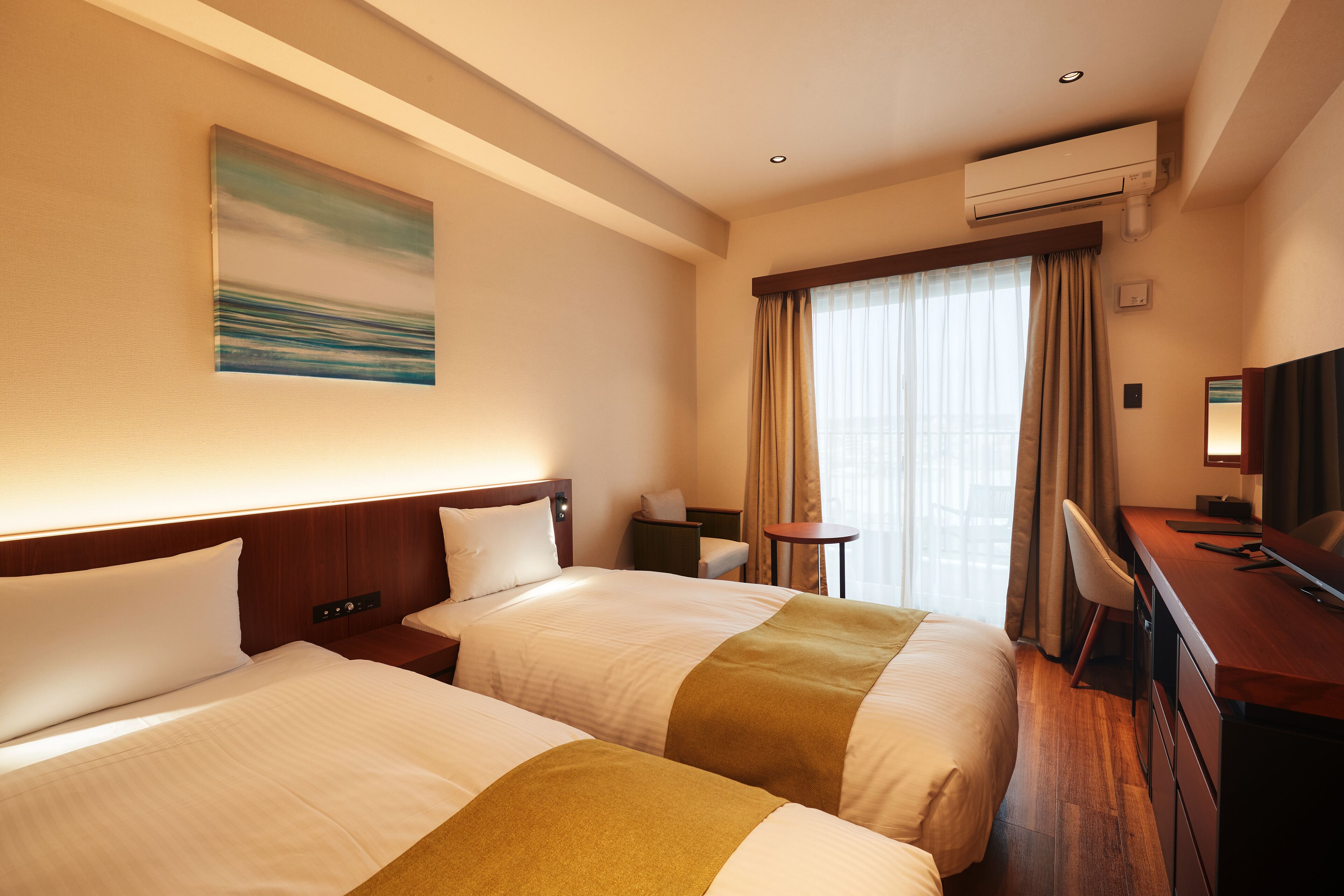 Une chambre d’hôtel avec deux lits, un bureau, une chaise, une télévision et un appareil de climatisation.