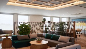 Un área de estar moderna con un sofá modular, mesas redondas y plantas en macetas.