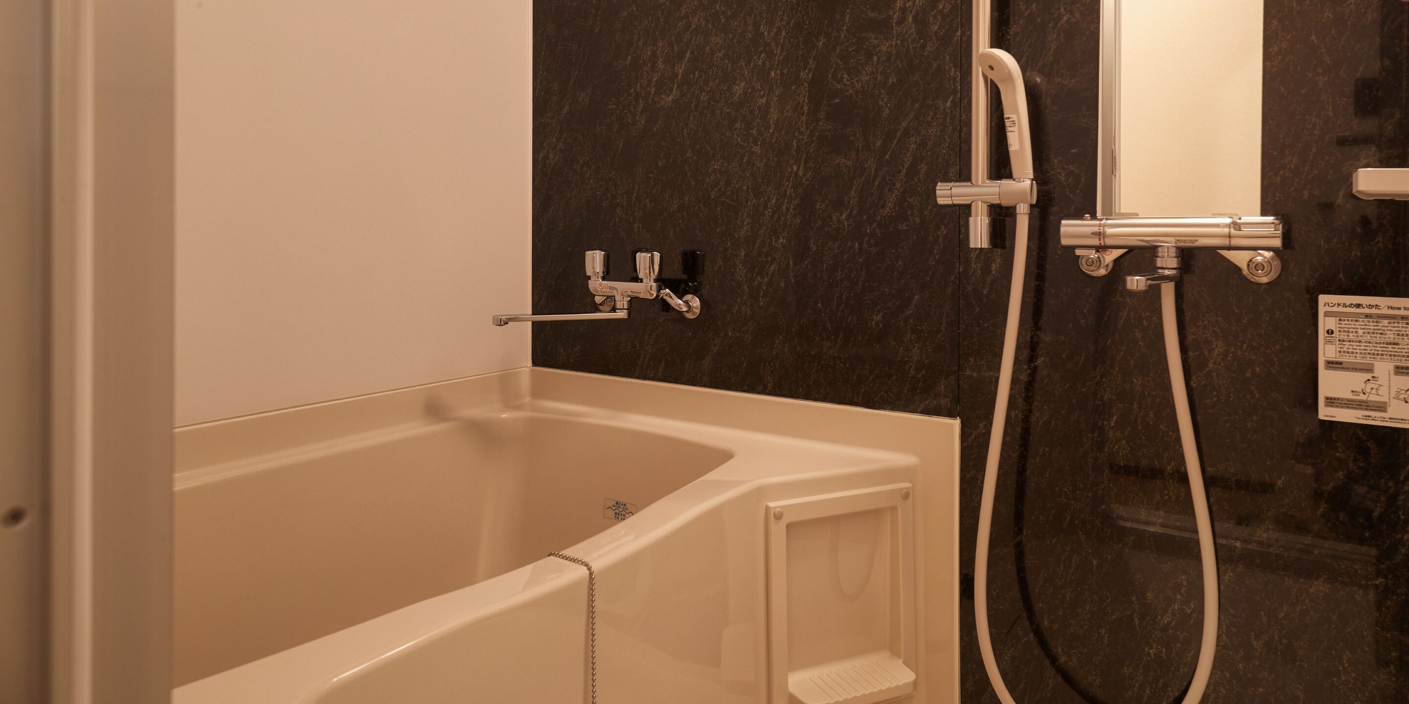 A bathtub with a shower attachment, a towel rack, and a wall-mounted control panel.