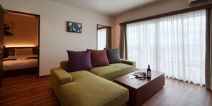 Una sala de estar moderna con un sofá verde, una mesa de centro de madera y una cama con cabecera.