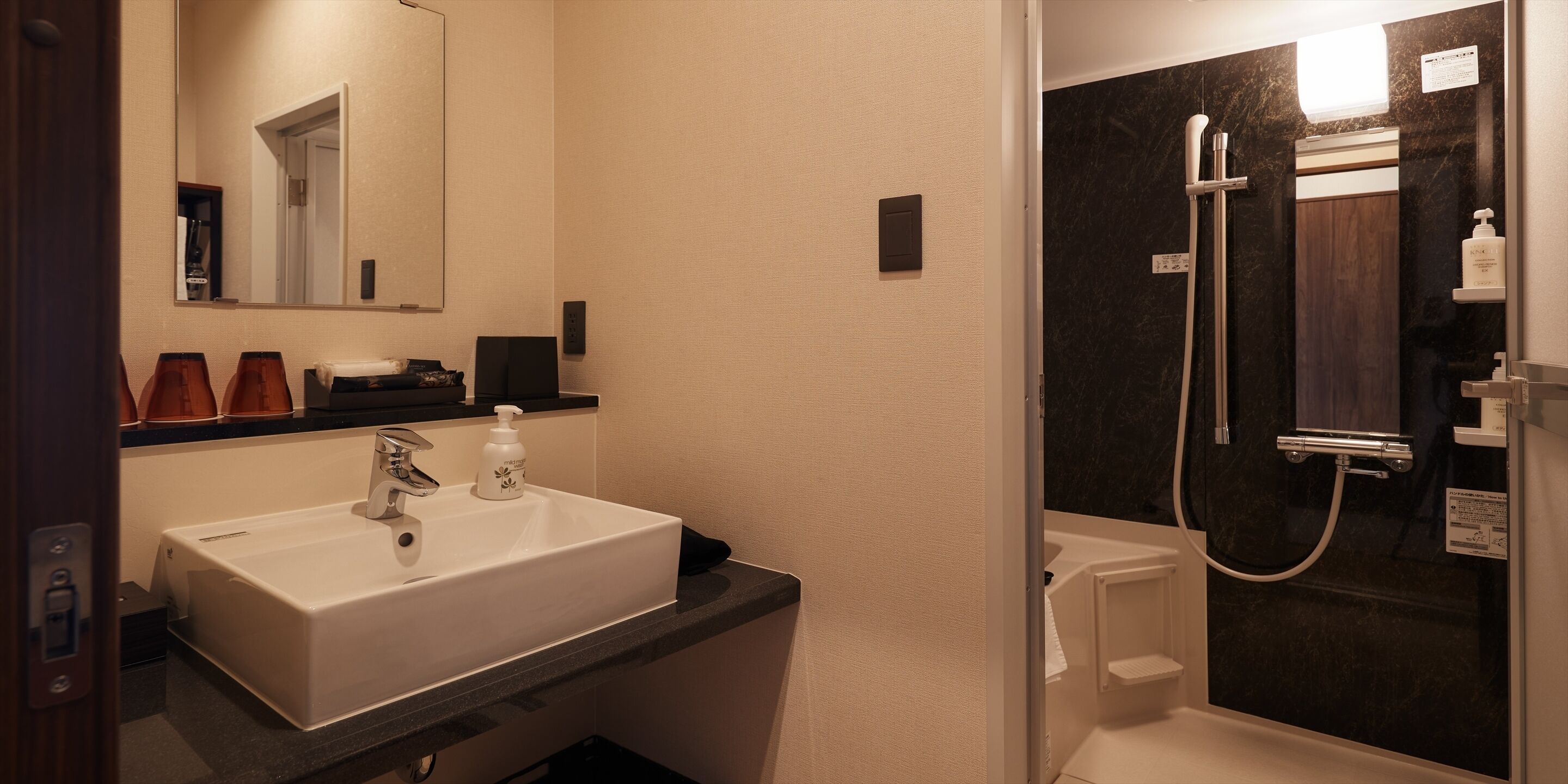 A bathroom with a white sink, a mirror, and a shower area.