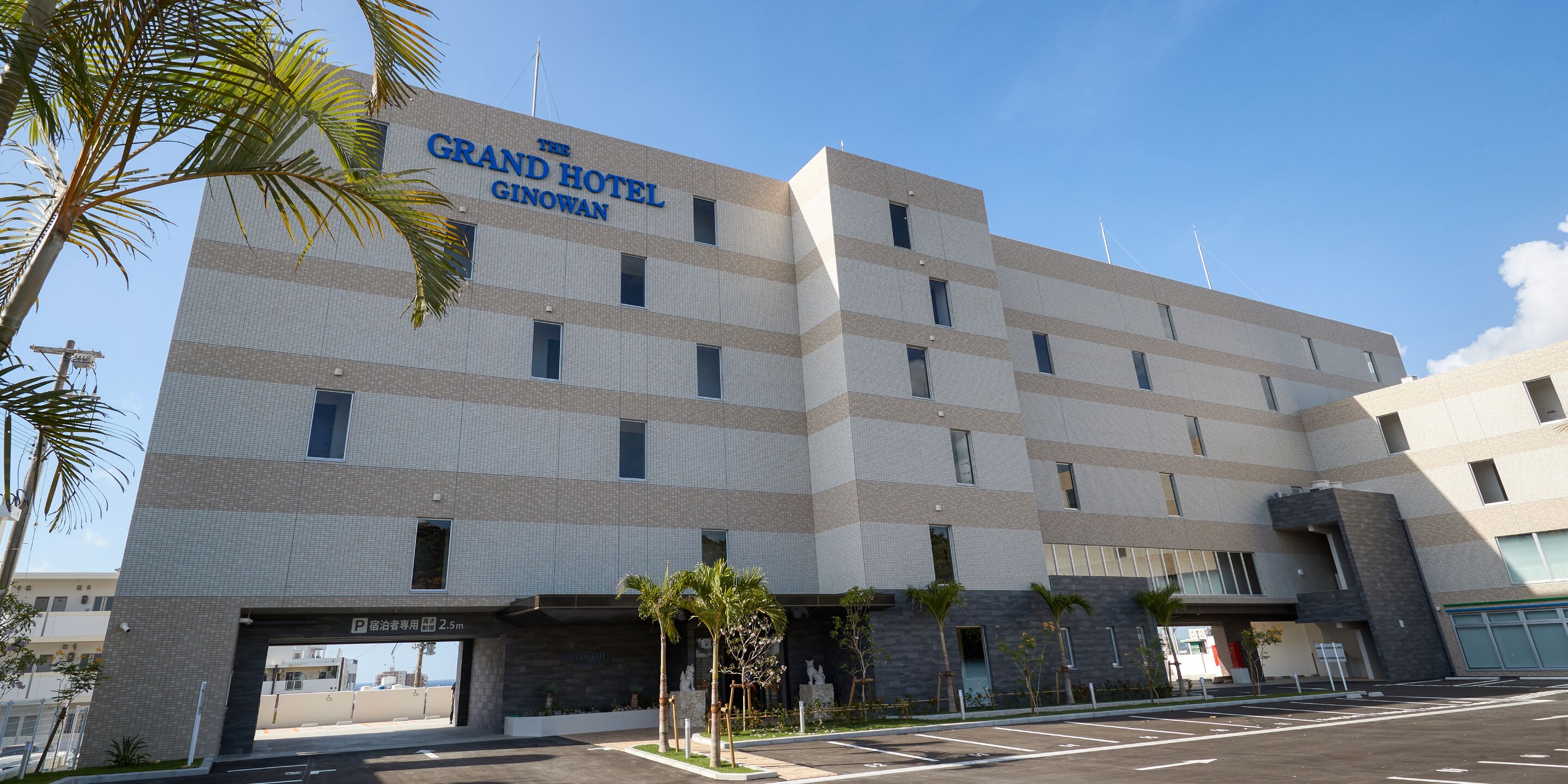 Un hotel de varios pisos con fachada de azulejos y un letrero que dice 'The Grand Hotel Ginowan'.