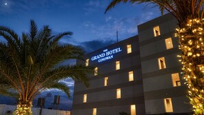 Un edificio de hotel con señalización iluminada, múltiples ventanas y palmeras circundantes.