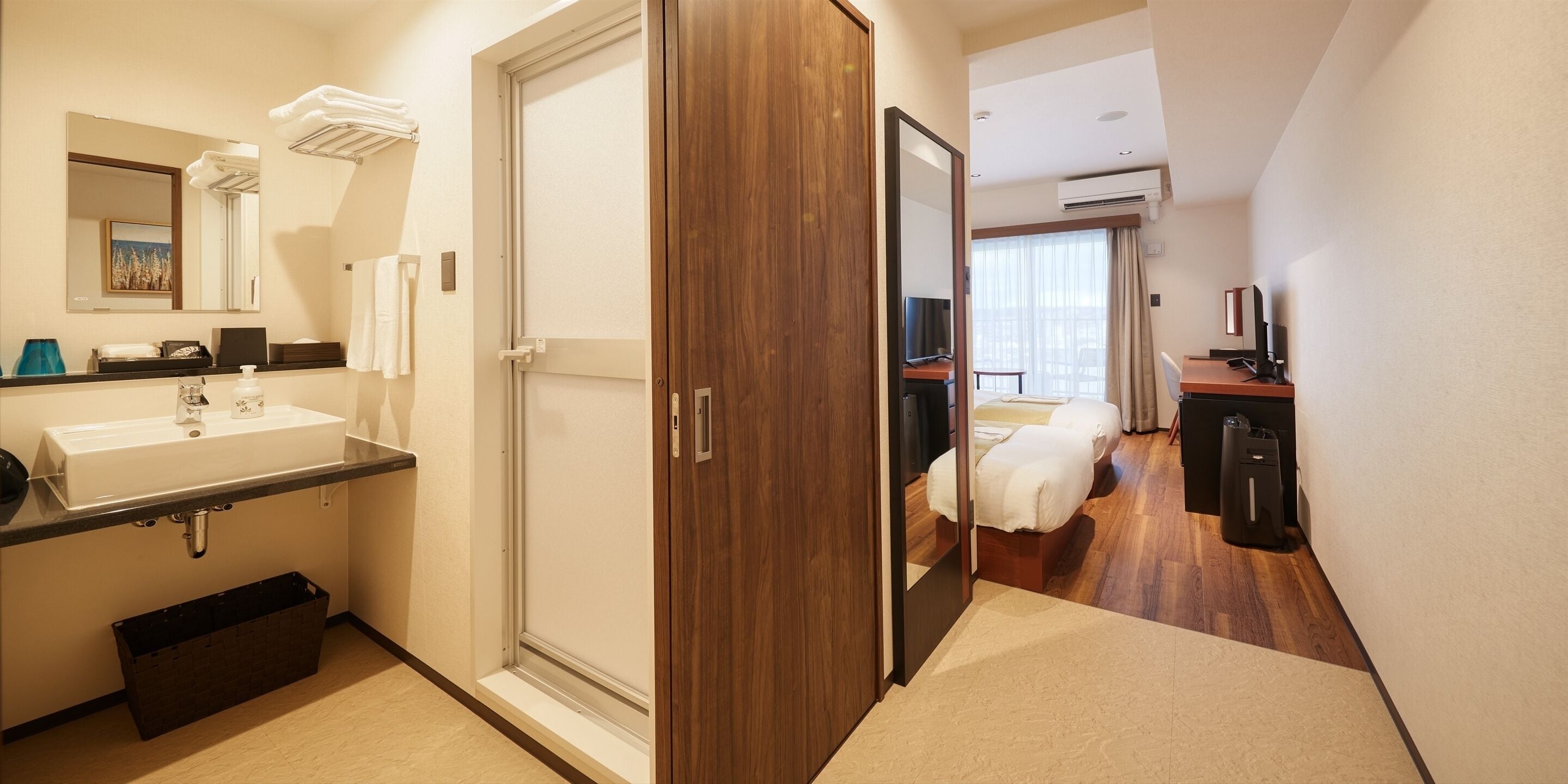 Ett hotellrum med badrum, säng, skrivbord och TV.