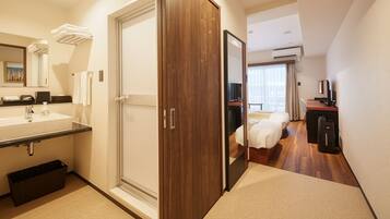 Quarto de hotel com banheiro, cama, escrivaninha e televisão.