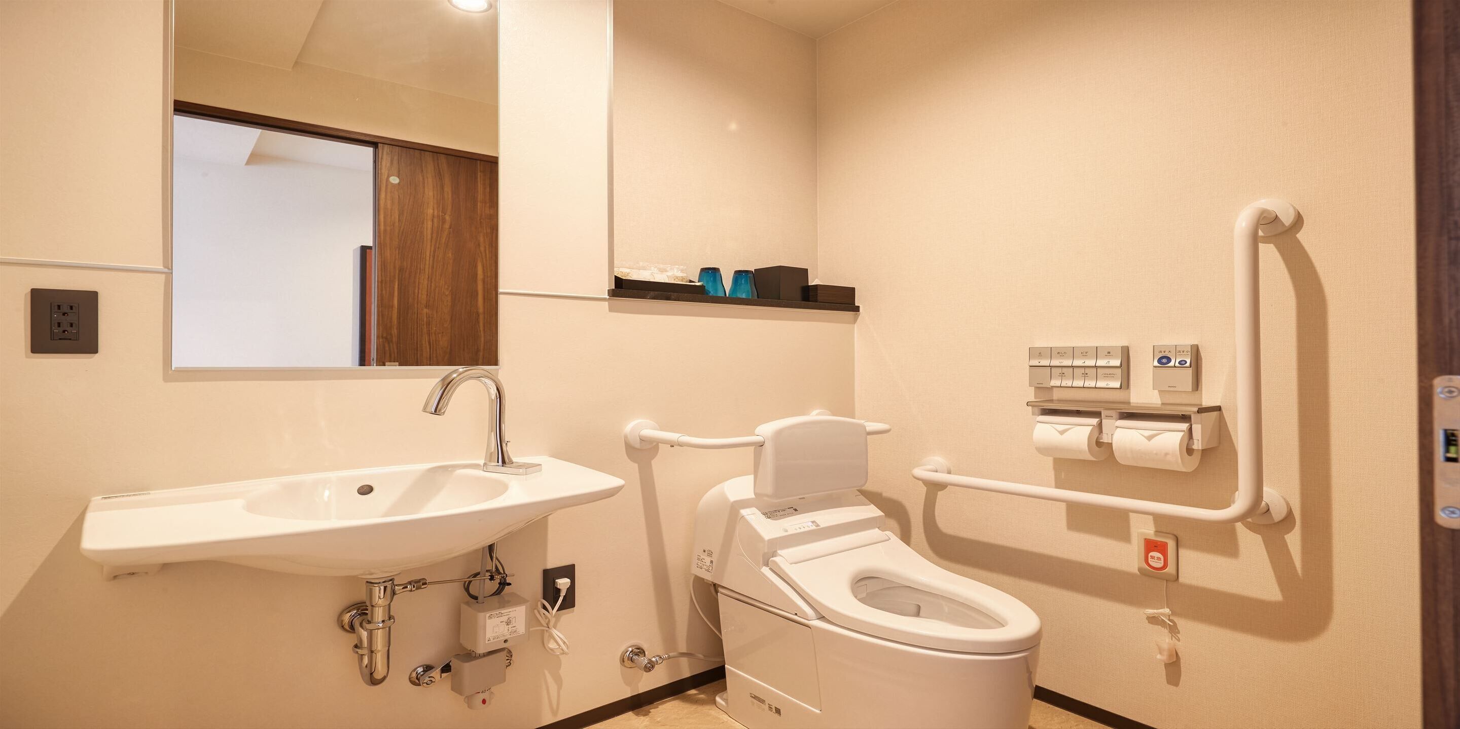 Un baño pequeño con lavamanos, inodoro y barras de apoyo.