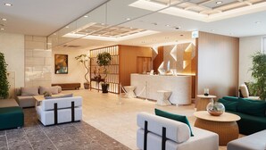Un vestíbulo moderno con zonas de estar, una recepción y plantas decorativas.