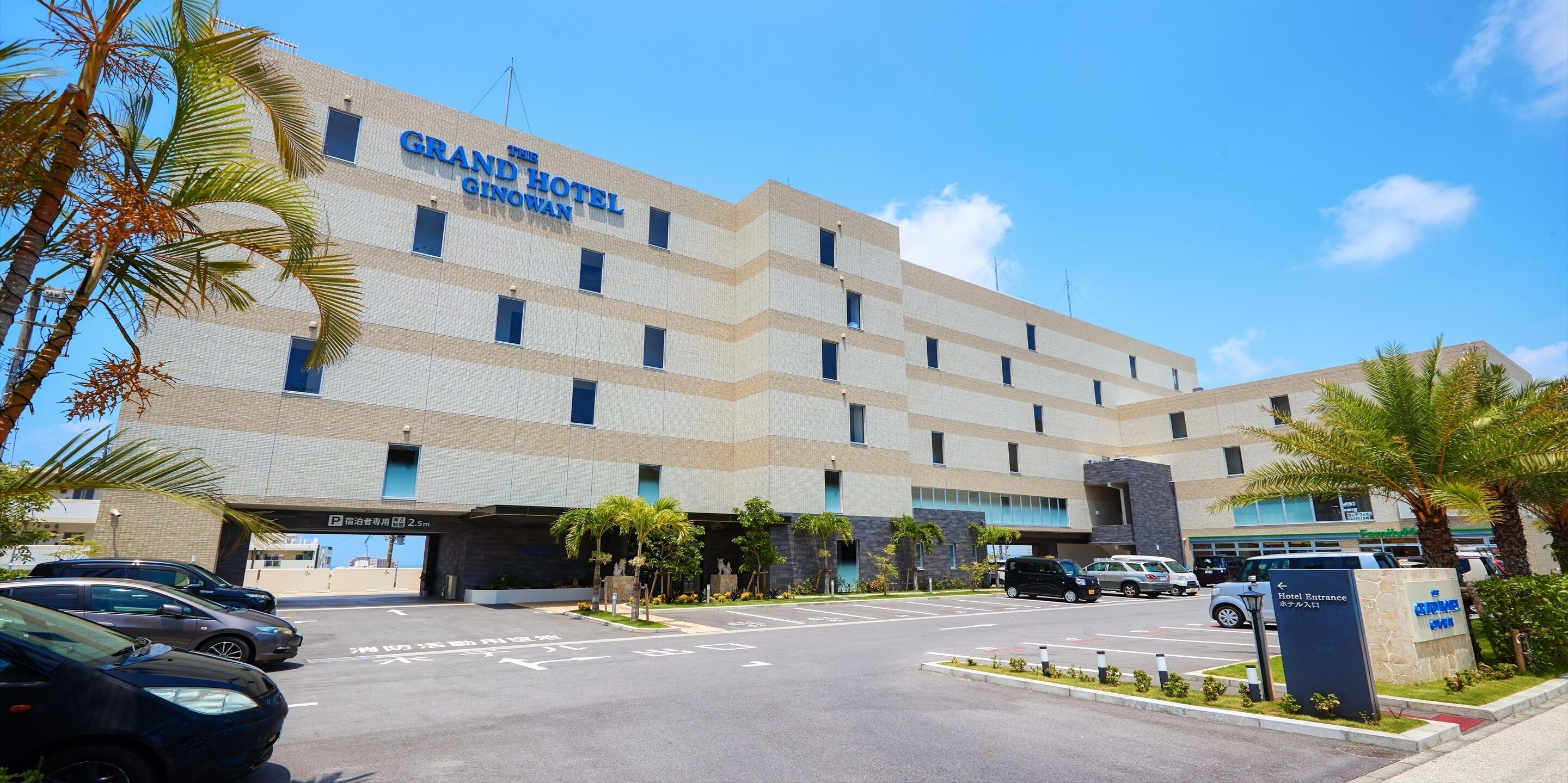 Le Grand Hôtel Ginowan, avec son architecture moderne, son parking et son ciel dégagé.