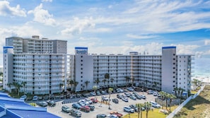 Um hotel com vários andares, estacionamento e vista para a praia.