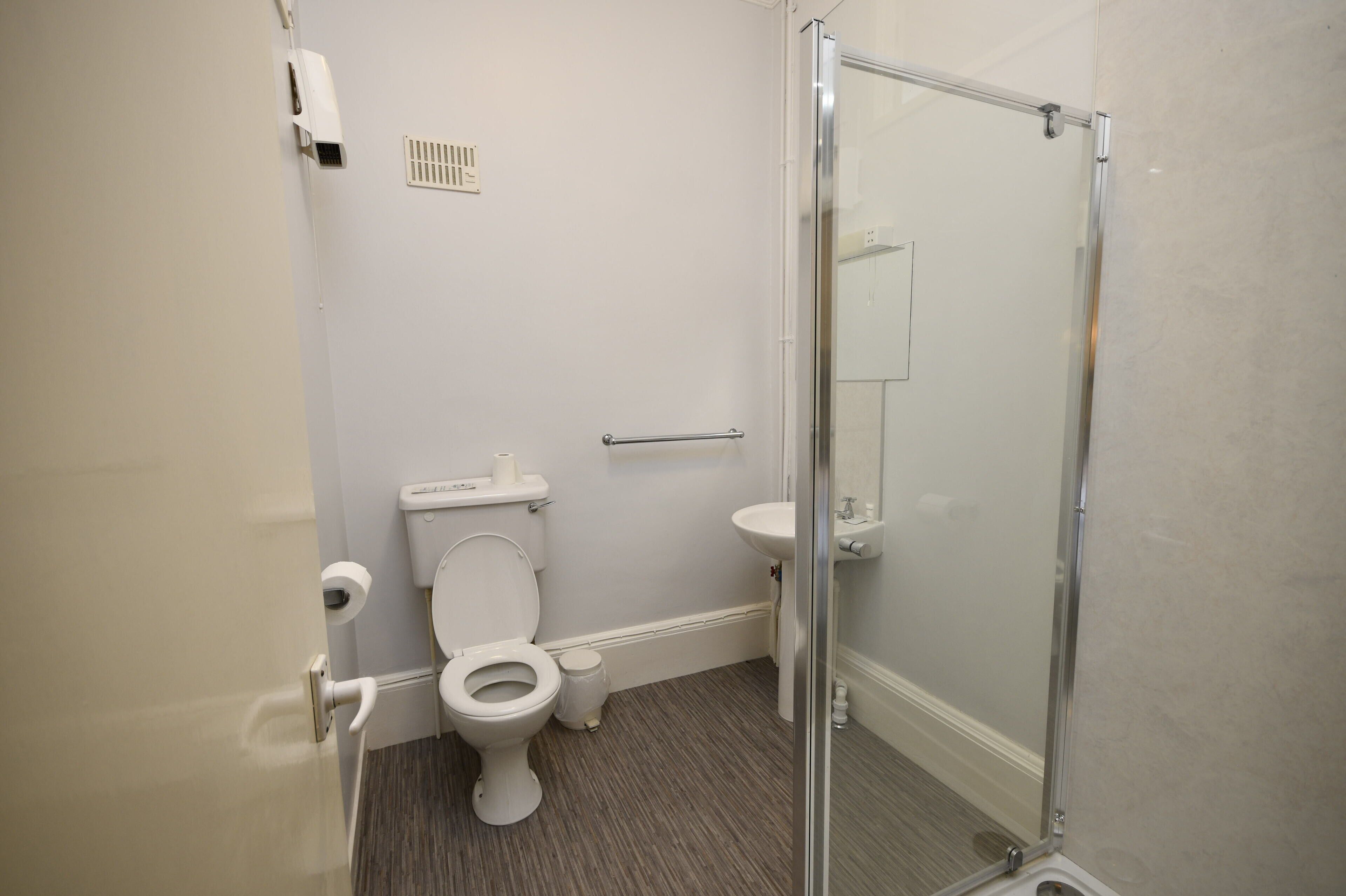 A modern bathroom with a toilet, sink, and glass-enclosed shower.