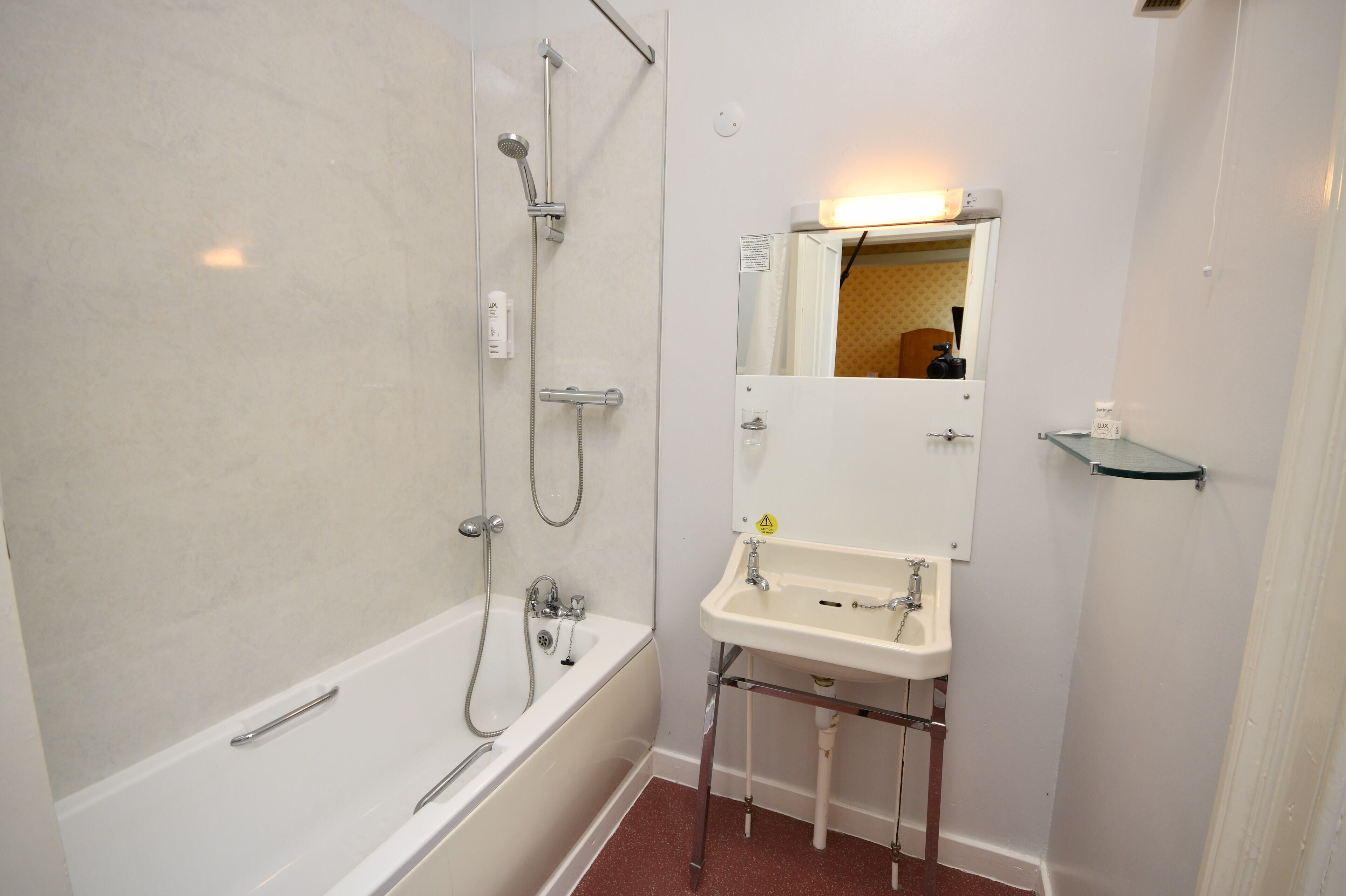 A bathroom with a bathtub, a sink, and a mirror.