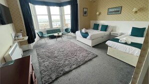 Una habitación de hotel con un ventanal grande, un sofá, una cama y una mesita.