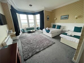 A hotel room with a large window, a sofa, a bed, and a small table. - The Stromness Hotel (Stromness)