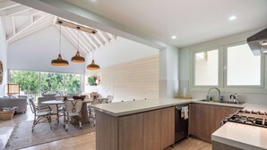 A modern kitchen with a central island, wooden cabinetry, and pendant lighting.