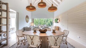 A dining area with a round wooden table, wicker chairs, and hanging wicker pendant lights.