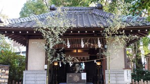 Un santuario japonés tradicional con tejado de tejas, pilares de piedra y un pequeño altar.