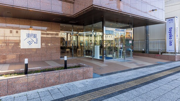 Un edificio moderno con entrada de vidrio, señalización de Toyoko Inn y un camino despejado que conduce a la entrada.