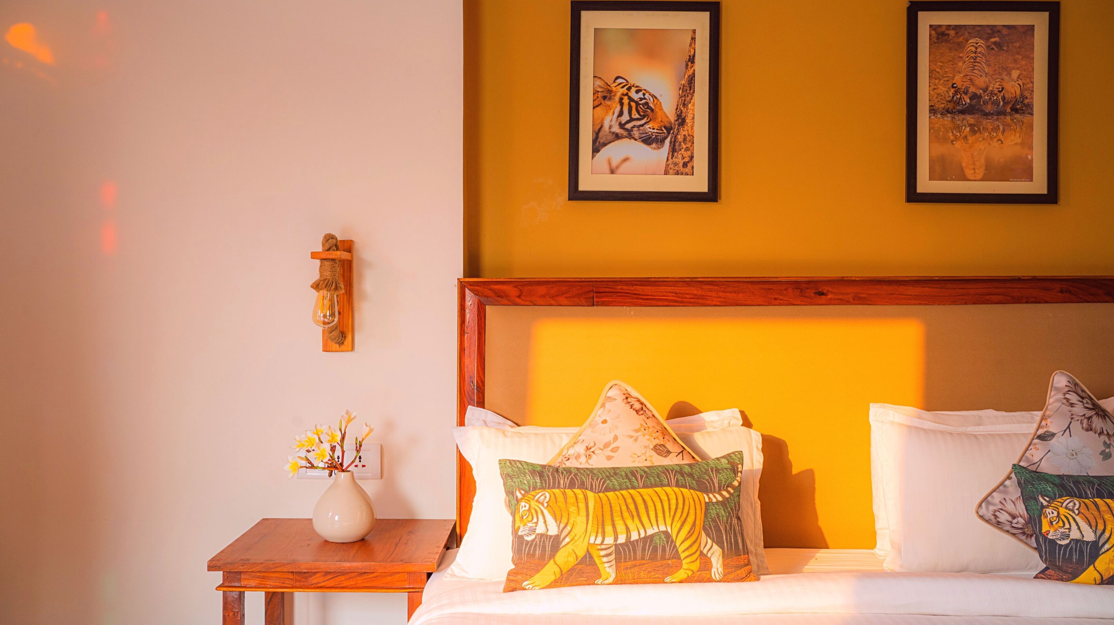 A bedroom with a wooden headboard, white bedding, and tiger-themed pillows.