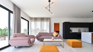 Ein modernes Wohnzimmer mit zwei Sofas, einem Couchtisch und einer Küchenzeile mit schwarzen Schränken und einer weißen Arbeitsplatte.