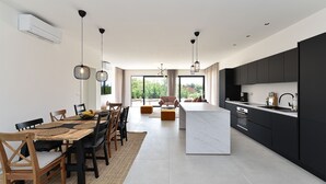 Eine moderne Küche mit schwarzen Schränken, einer zentralen Kochinsel und einem Essbereich mit Holztisch und -stühlen.