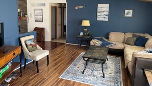 A living room with a sofa, a coffee table, a chair, a lamp, and a rug. There is a door leading to another room. - Cabana Too Smith Mountain Lake (Moneta)