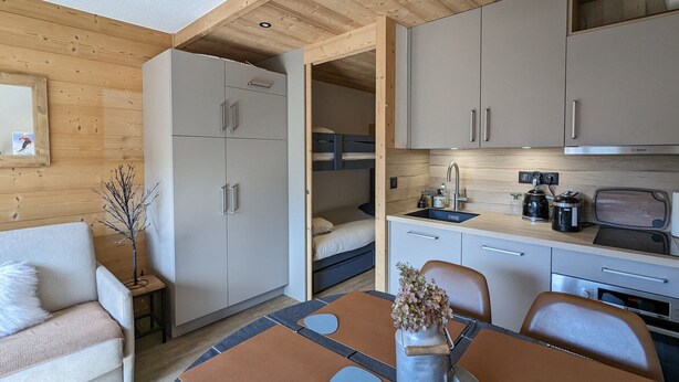 Un espace de vie compact comprenant un coin cuisine, un coin repas et un espace nuit.