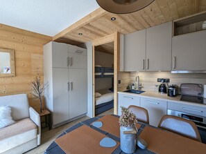 Een compacte leefruimte met een kitchenette, een eethoek en een slaapgedeelte.