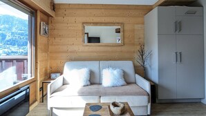 Une pièce chaleureuse avec un mur en bois, un canapé blanc agrémenté de coussins moelleux, une petite table avec un bol, et un meuble.