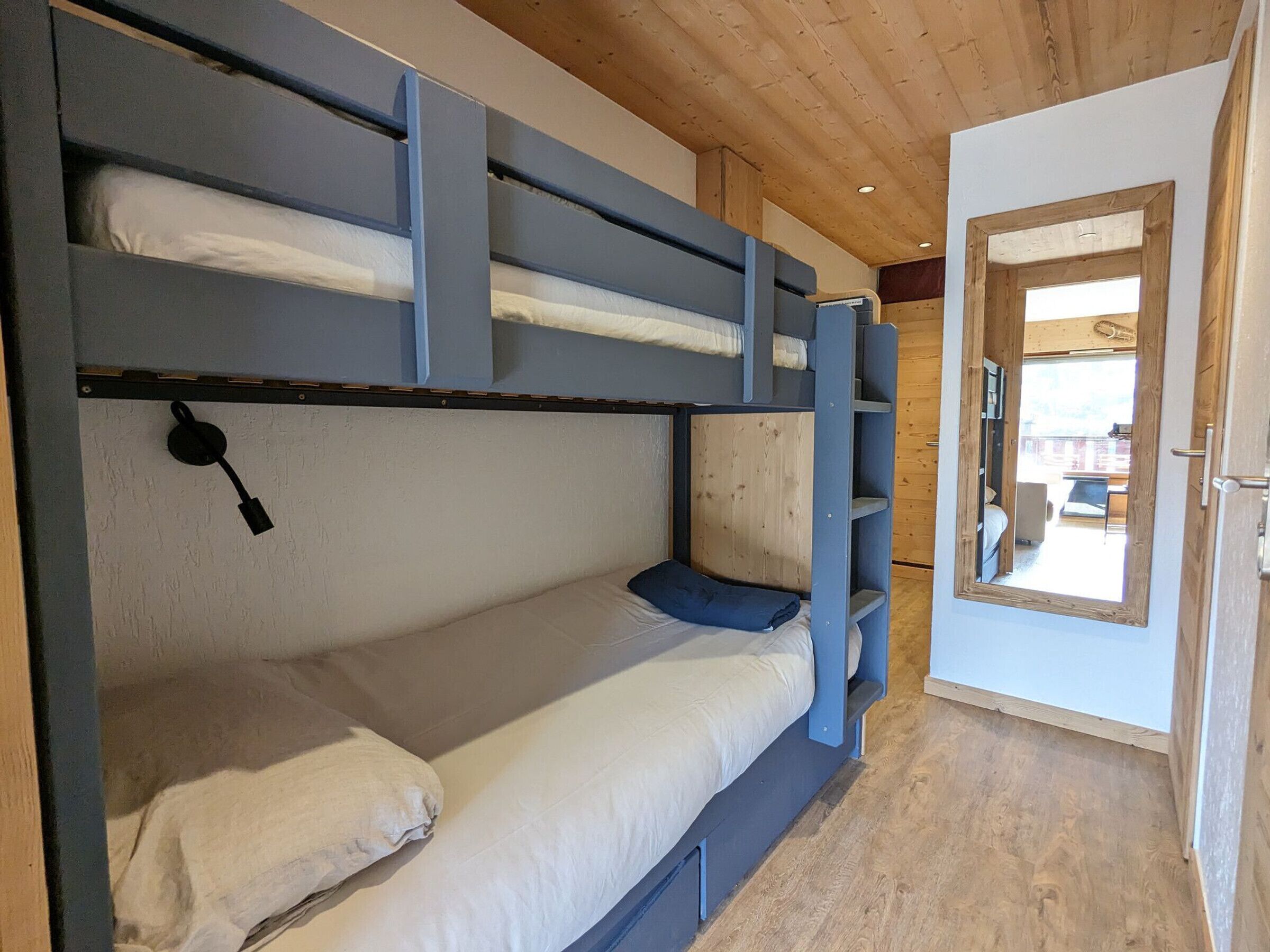 Ein Schlafzimmer mit Etagenbetten, Holzboden und einer Tür zu einem Außenbereich.