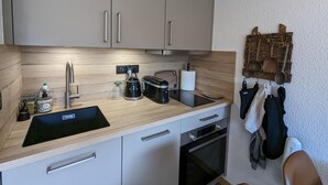 Une cuisine moderne dotée d’un plan de travail en bois, d’appareils électroménagers en acier inoxydable et d’un porte-ustensiles suspendu.