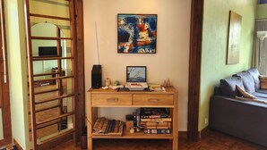 Ein gemütliches Wohnzimmer mit einem Holztisch, einem Bücherregal, einem Wandbild und einem bequemen Sofa.