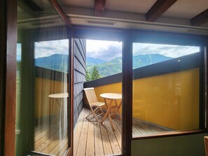 Un balcon doté d’un plancher en bois, de deux chaises en bois et d’une table.
