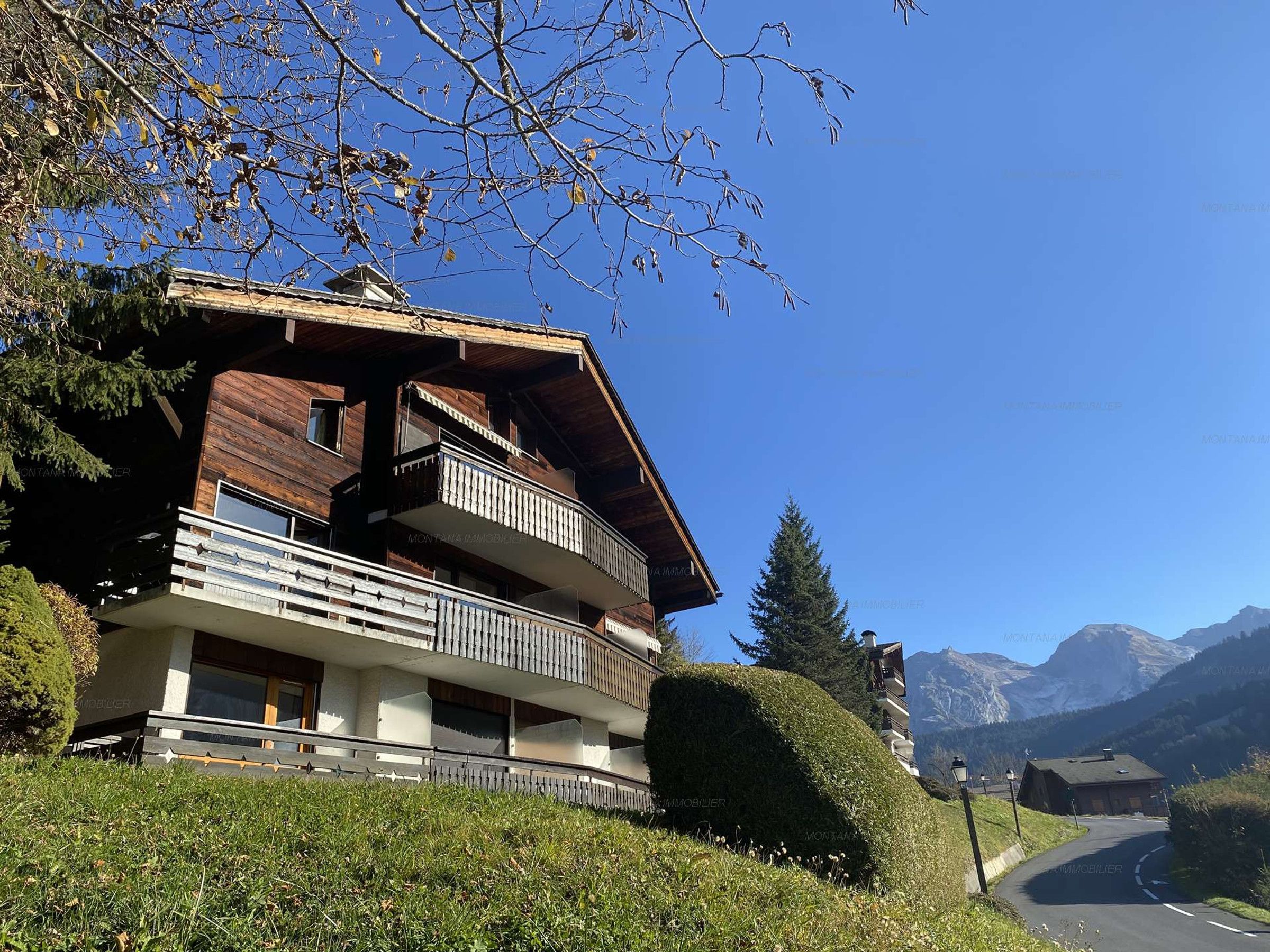 A multi-story wooden building with balconies, set against a mountainous backdrop.