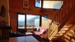 A wooden interior with a dining area, a sofa, and a staircase. - Pleasant mountain-style apartment for 6 near shops and cable cars (Le Grand-Bornand)