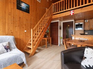 A wooden interior with a staircase, a dining area, and a kitchen. - Pleasant mountain-style apartment for 6 near shops and cable cars (Le Grand-Bornand)