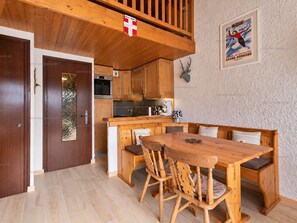 A wooden interior with a dining area, kitchen, and a mounted deer head on the wall.