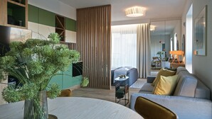 Uma sala de estar moderna com uma mesa de jantar redonda, um sofá e uma grande planta em vaso.