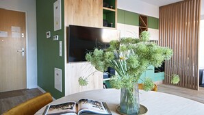 Uma sala de estar moderna com um armário de madeira, uma TV de tela plana e uma parede verde de destaque.