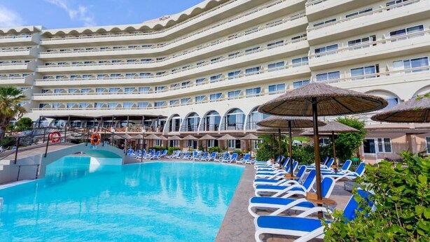 A hotel with a large pool, multiple balconies, and sun loungers. - Olympos Beach (Rhodes)