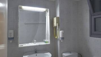 Een badkamer met een wastafel op voetstuk, toilet en een klein krukje.
