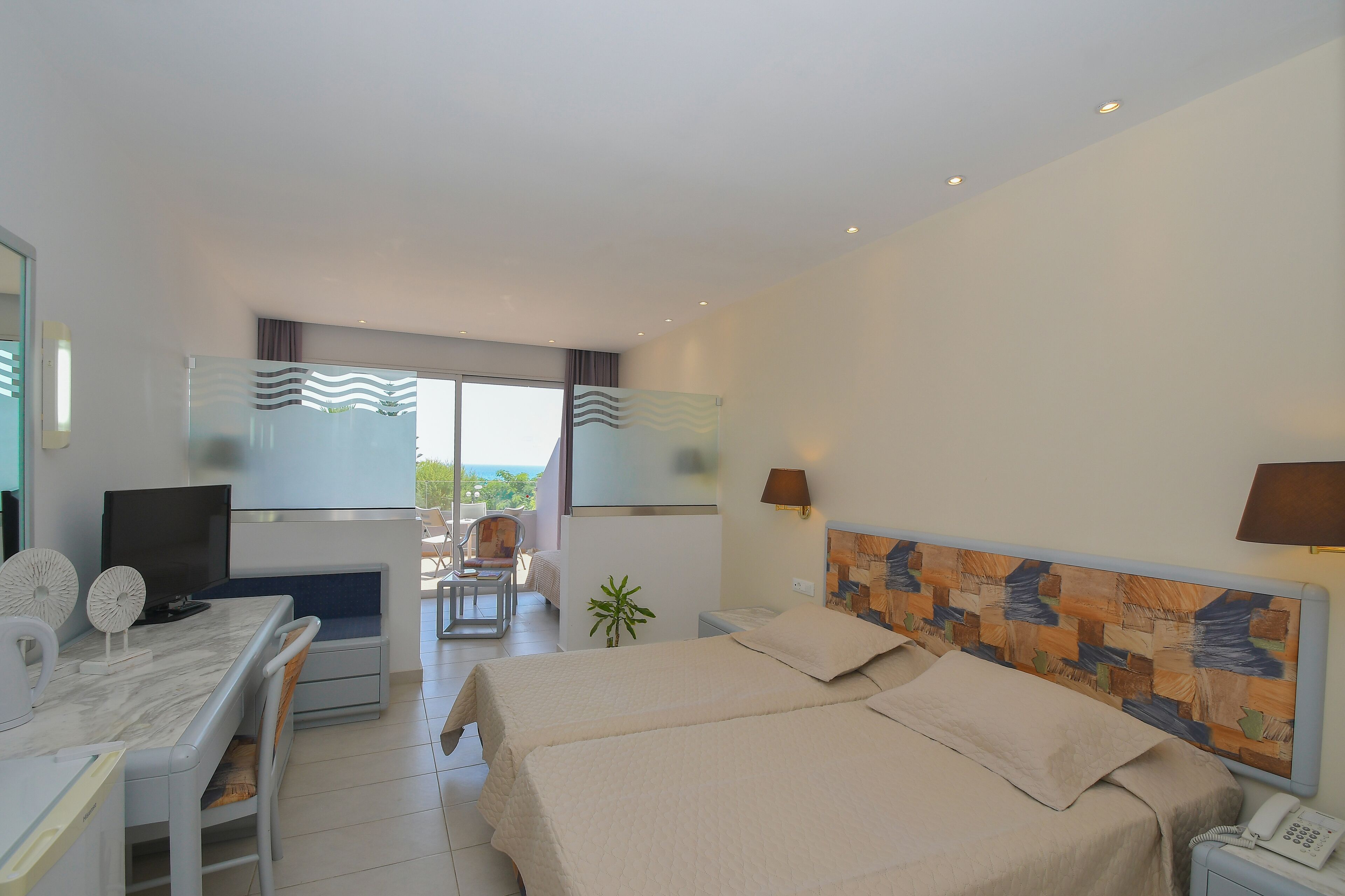 Camera d'albergo con letto, scrivania, sedia, televisore e vista sull'esterno.