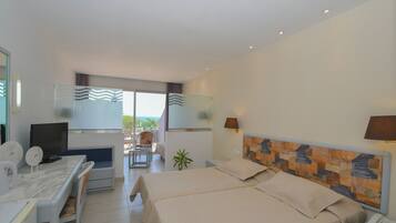 Camera d'albergo con letto, scrivania, sedia, televisore e vista sull'esterno.