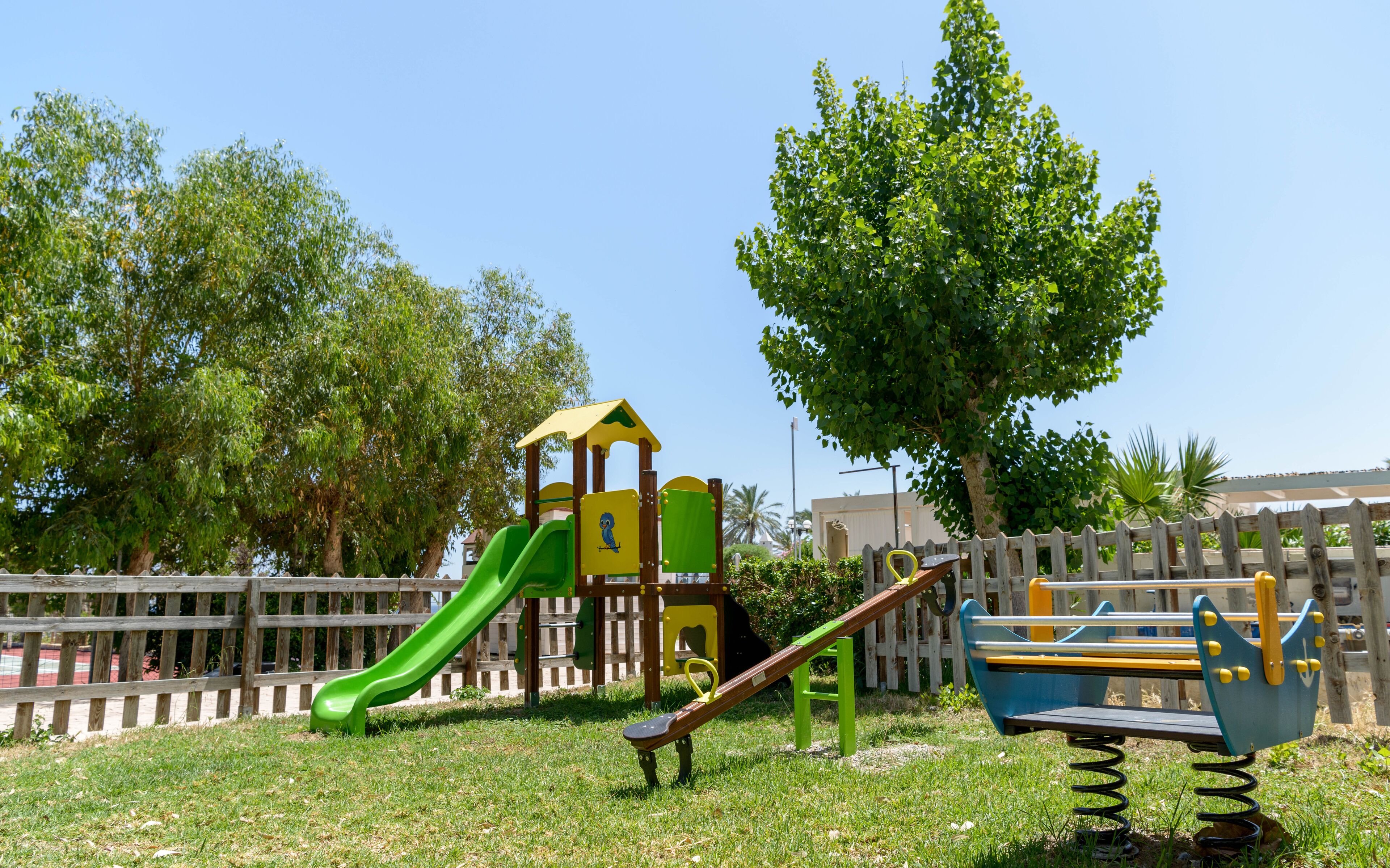 Une aire de jeux avec un toboggan, une balançoire et des structures d’escalade.